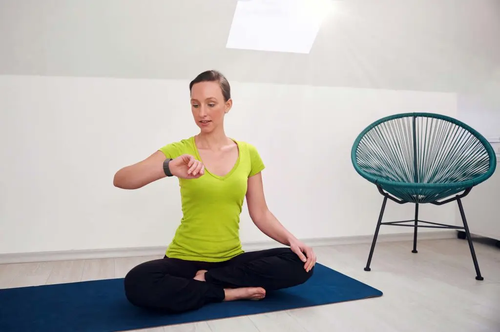 Frau mit Smartwatch auf Yoga-Matte